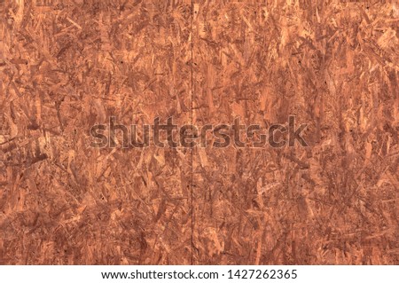 The structure of the wood chipboard, painted in red-brown color close-up. Abstract background