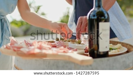 Romantic couple, man and woman toasting with red wine and eating finger food appetizer at warm sunset.Food detail shot. Friends italian trip in Umbria.4k slow motion Royalty-Free Stock Photo #1427287595