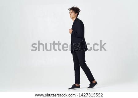 A business man in a full-length suit on a light background walking to the side                   