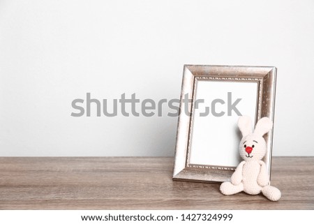 Photo frame and adorable toy bunny on table against light background, space for text. Child room elements