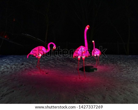 Glowing statue of pink flamingos in a winter park