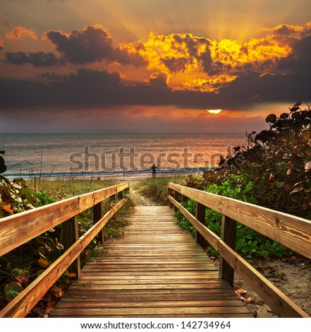 Boardwalk on beach at sunrise Royalty-Free Stock Photo #142734964