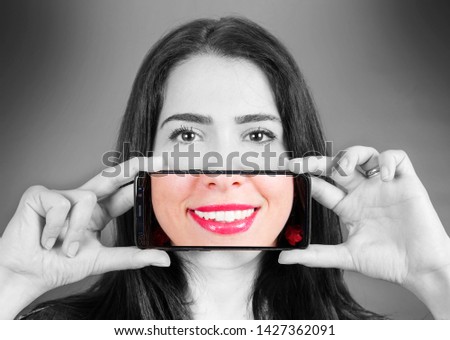 woman with smartphone that takes a picture of her smile