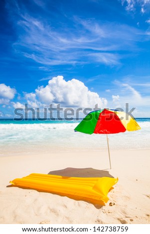 colorful sunshade and yellow air mattress at a beautiful beach with a turquoise sea