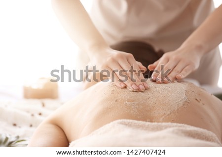 Young woman undergoing treatment with body scrub in spa salon, closeup Royalty-Free Stock Photo #1427407424