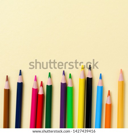 Multicolored wooden pencils for school on yellow paper background. School and office stationery on yellow background. Concept back to school. Square image. Top view.