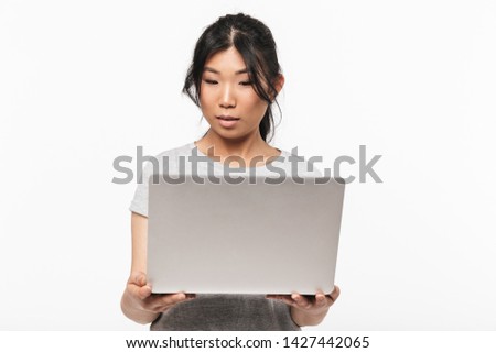 Photo of asian thinking beautiful young woman posing isolated over white wall background using laptop computer.
