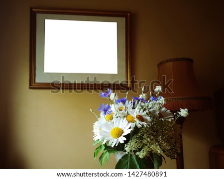 Picture frame in interior and bouquet of flowers