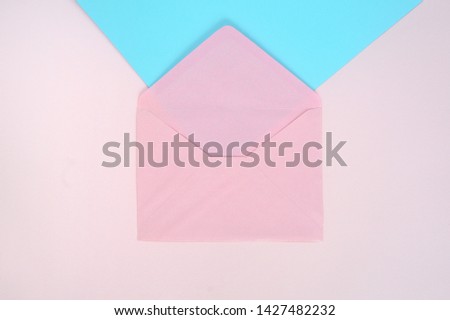 Open pink envelope on pink and blue background. Top view