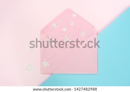 Open pink envelope with snowflake on pink and blue background. Top view, Christmas concetp style