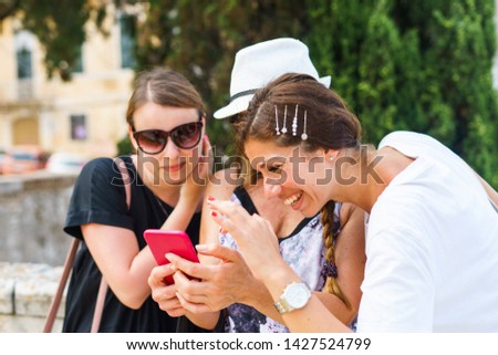 Three woman looking to the smart-phone mobile phone searching for the tourist information photos in the Corfu town