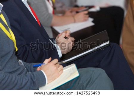 Businessmen taking notes at a conference or seminar.