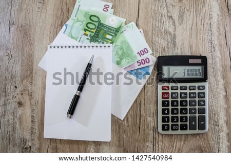 Euro banknotes in envelope, notebook, pen and calculator on the table