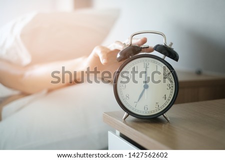 Woman sleep on the bed turns off the alarm clock wake up at the morning, Selective focus. Royalty-Free Stock Photo #1427562602