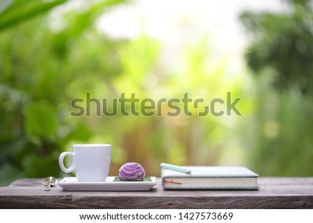 White cup with purple dessert and notebooks at outdoor