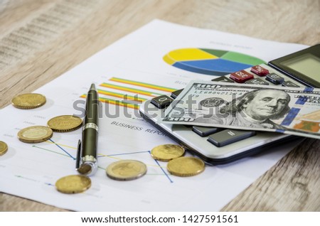 Dollars, calculator, pen and coins on business chart