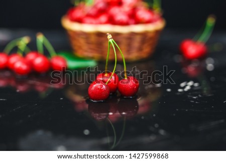 Fresh cherries placed in a basket and black cherries with water splashes. Selective focus