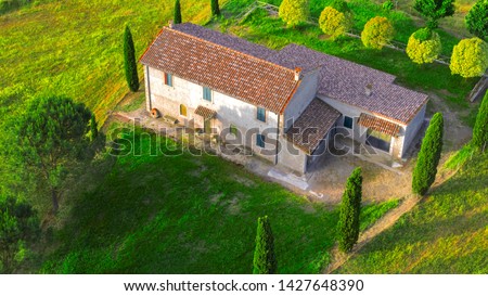 Aerial view of a villa at sunset. The country house has a large garden with trees and plants and is surrounded by nature in the hills of Tuscany, Italy.  Royalty-Free Stock Photo #1427648390