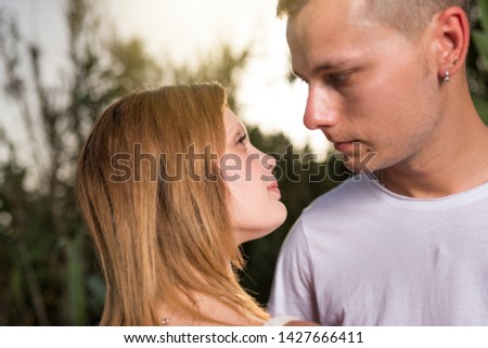 Close up of a smiling young couple embracing at the park, relaxing