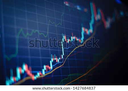 Closeup financial chart with uptrend line candlestick graph in stock market on blue color monitor background Royalty-Free Stock Photo #1427684837