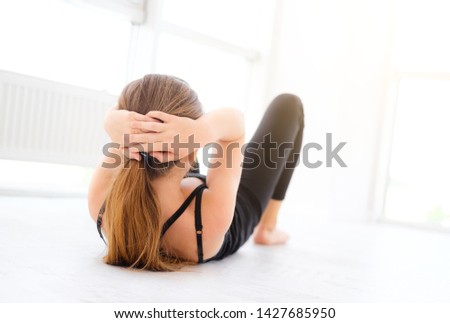 young girl doing abs exercises on a floor in light room