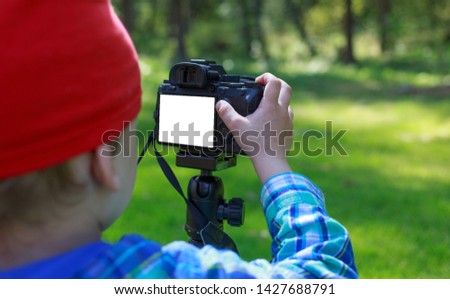 Boy using digital camera in summer forest. Mockup image