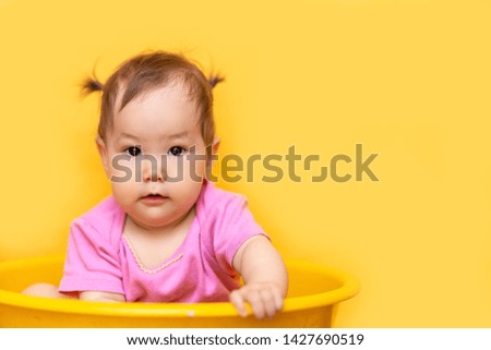 1 year old playful asian caucasian girl mixed race kazakh and german girl on yellow background.