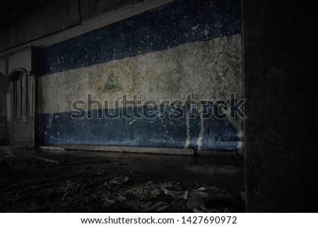 painted flag of nicaragua on the dirty old wall in an abandoned ruined house. concept