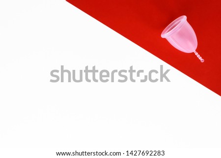 Menstrual cup is reusable product for women period intimate hygiene. Take care of your body and planet with zero waste solution. White and red background with copy space.