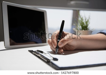 Business woman hand is writing on a notepad with a pen. Close up