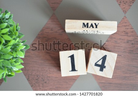 Date of May with leaf on diamond pattern table for background.