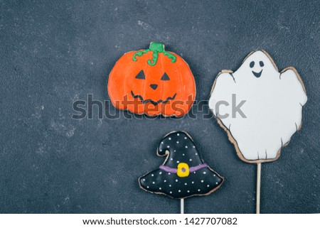 Halloween background. Holiday gingerbread cookies - hat, pumpkins and ghost on wooden board on rustic background. Fall Autumn Concept. Top view, copy space