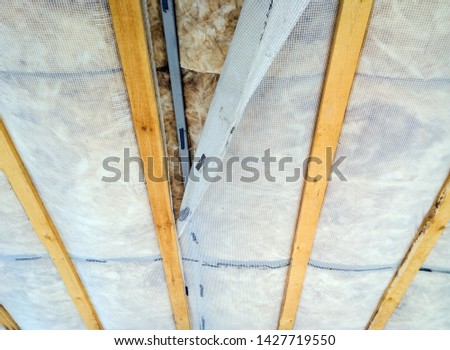 Warming of the ceiling with mineral basalt wool and reinforced polyethylene film. Thermal insulation of the house, energy efficiency for heating in winter. Selective focus. Royalty-Free Stock Photo #1427719550