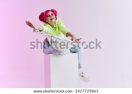 stylish woman with pink hair sits on a cube