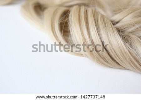 Beautiful hair. Light hair. Curl. Strand of hair. Curl on white background. With free space for text. For a poster or business card.