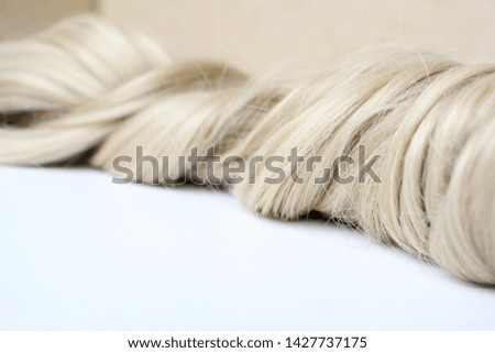 Beautiful hair. Light hair. Curl. Strand of hair. Curl on white background. With free space for text. For a poster or business card.