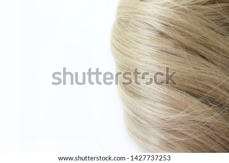 Beautiful hair. Light brown hair. Hair is gathered in a bun on a white background. With free space for text. For a poster or business card.