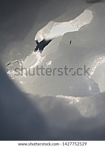 Melting icy snow manin landscape. People walk in winter sunny day around. Holes in snowman body
