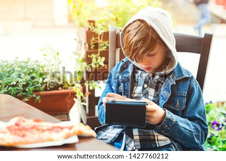 Boy addicted online games outdoors. Boy use phone and plays games. Schoolboy plays on smartphone after school
