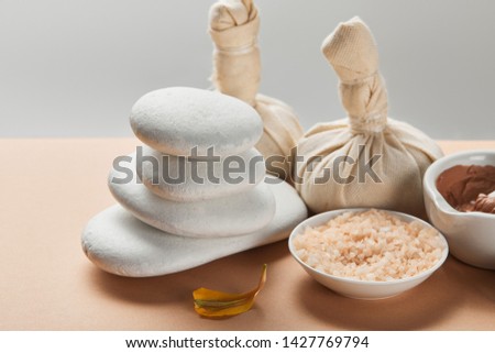 sea salt, clay, stones and yellow flower petal on beige surface isolated on grey