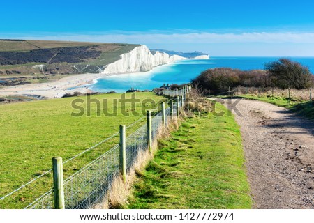 Walk in Cuckmere Haven near Seaford, East Sussex, England. South Downs National park. View of blue sea, cliffs, beach, green fields, selective focus Royalty-Free Stock Photo #1427772974