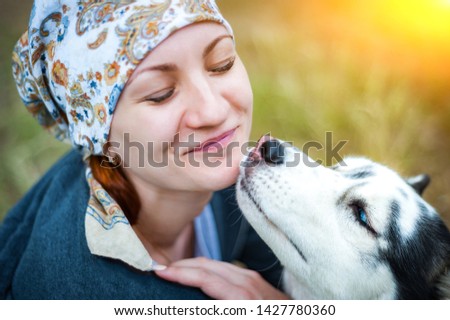 A young girl while walking in the Park with a dog, hugging the dog Husky and kissing.
