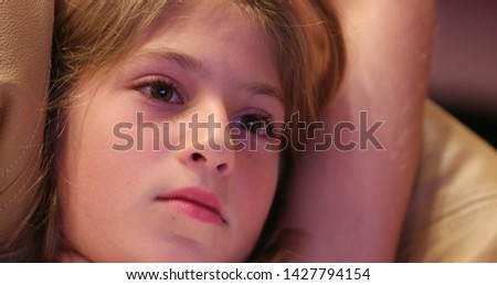Closeup of little girl watching tv screen hypnotized by story