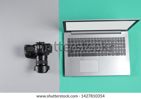 Modern laptop with camera on color paper background. Equipment modern photographer. Top view