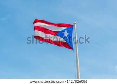 Puerto Rico flag fluttering in the wind on the flagpole against the blue sky