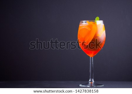 Cocktail aperol spritz on black background. Summer alcohol cocktail with orange fruit and fresh mint. Italian cocktail aperol spritz on wooden boards