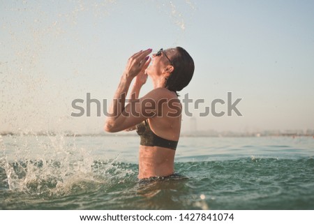 Joyful woman splashing water in the sea