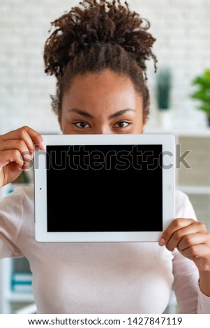 Mockup image of black empty blank screen of ipad in the female hand, peeking from behind tablet