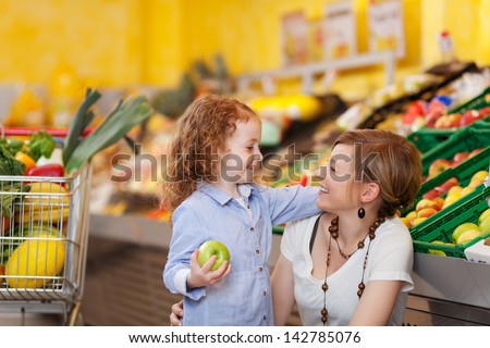 Beautiful photograph of a mother and daughter in the food department looking at each other and smiling.