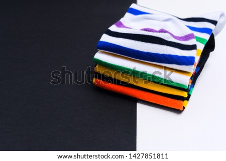 Set of colorful striped white and black socks on white and black background with copy space. Selective focus. Warm funny clothes for hipster